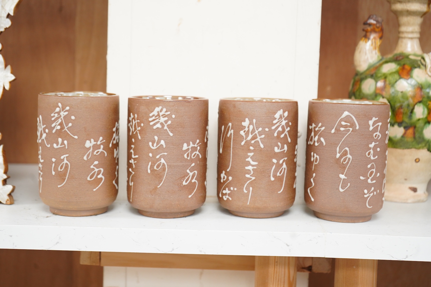 A set of four Japanese studio pottery beakers with calligraphy, 11cm high